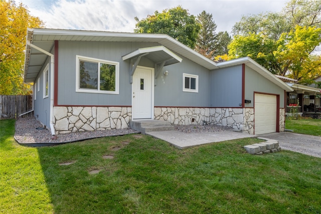 view of front facade with a garage, stone siding, and a front lawn