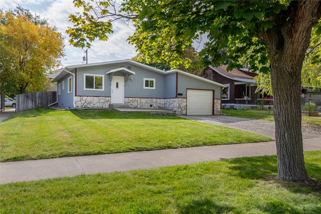 view of front facade featuring driveway, stone siding, an attached garage, fence, and a front lawn