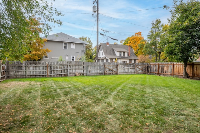 view of yard with a fenced backyard and a gate