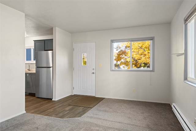 foyer with plenty of natural light, baseboards, baseboard heating, and dark colored carpet