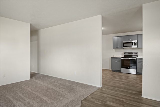 interior space featuring dark wood finished floors, stainless steel appliances, gray cabinets, light countertops, and baseboards