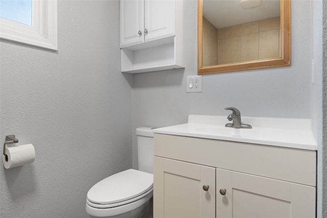 half bath featuring toilet, a textured wall, and vanity