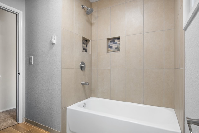 full bath featuring a textured wall, bathtub / shower combination, and baseboards