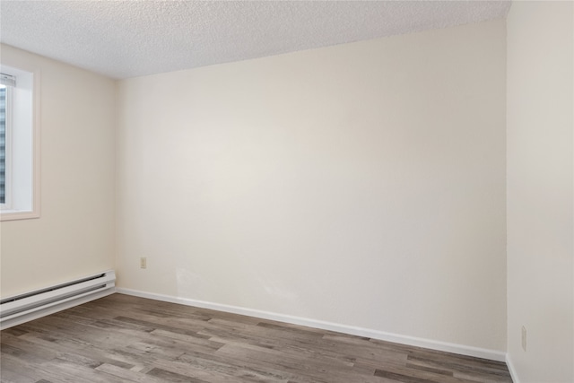 empty room with a textured ceiling, baseboard heating, wood finished floors, and baseboards