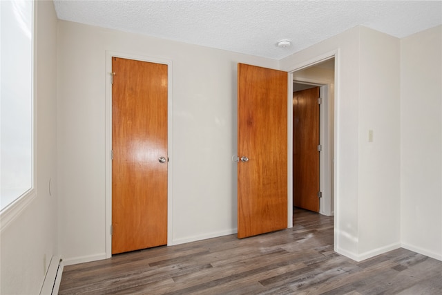 unfurnished bedroom featuring a baseboard radiator, a textured ceiling, baseboards, and wood finished floors