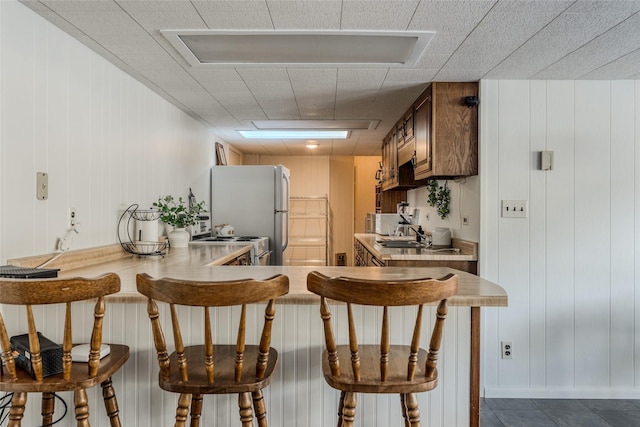 237 Lake Blaine Dr, Kalispell, MT 59901 - kitchen with white appliances, wood walls, light countertops, a sink, and a breakfast bar area