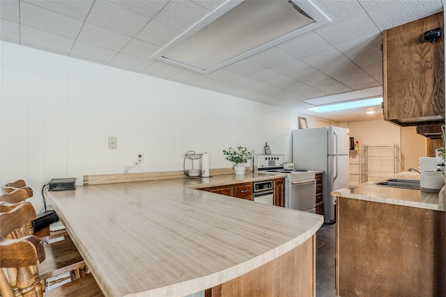 237 Lake Blaine Dr, Kalispell, MT 59901 - kitchen with white appliances, brown cabinetry, a peninsula, a sink, and light countertops