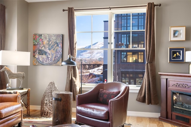 sitting room with a glass covered fireplace, wood finished floors, and baseboards