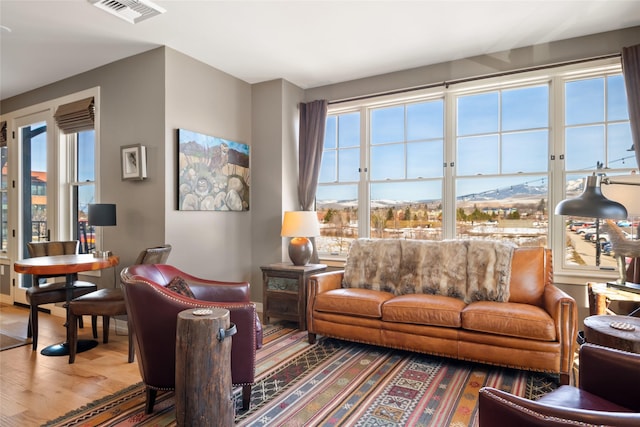 living area with plenty of natural light, visible vents, and wood finished floors