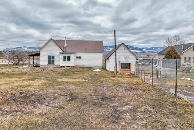 back of house featuring fence, a mountain view, and metal roof