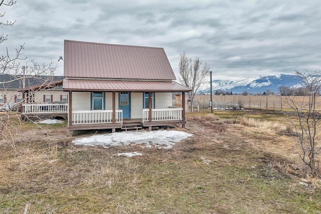 view of front of property featuring covered porch, metal roof, and fence