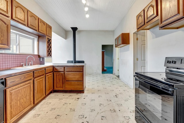 kitchen with brown cabinets, light floors, light countertops, electric range, and a sink