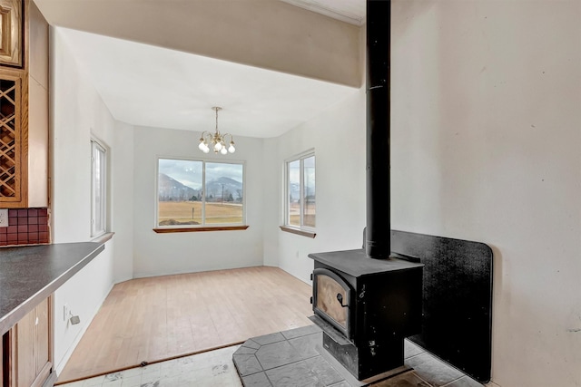 room details featuring tasteful backsplash, a wood stove, a chandelier, and wood finished floors