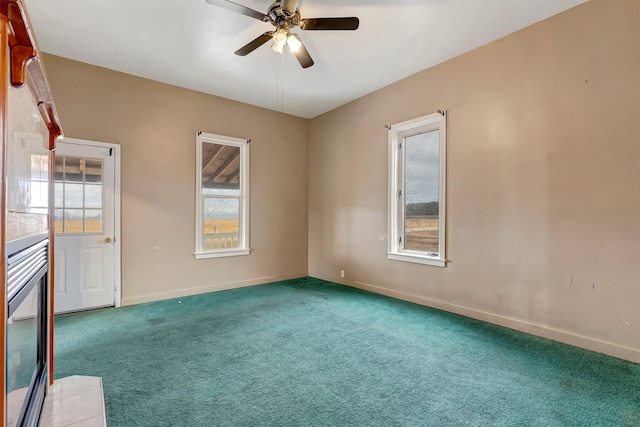 carpeted spare room featuring ceiling fan and baseboards