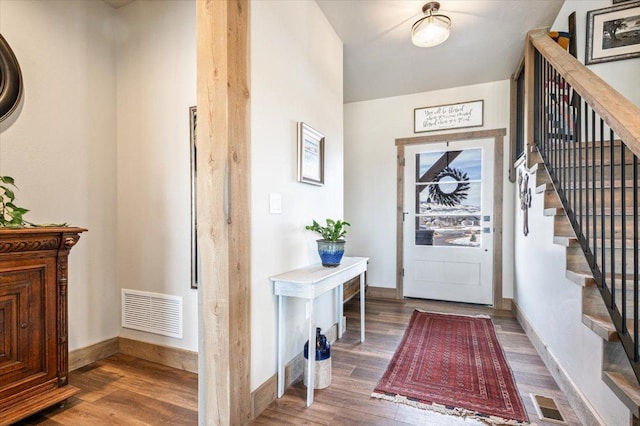 foyer with stairs, wood finished floors, and visible vents