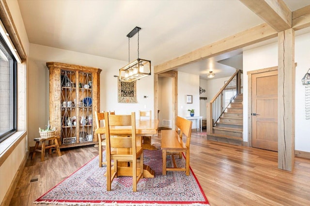 dining space with visible vents, stairway, light wood-type flooring, beamed ceiling, and baseboards