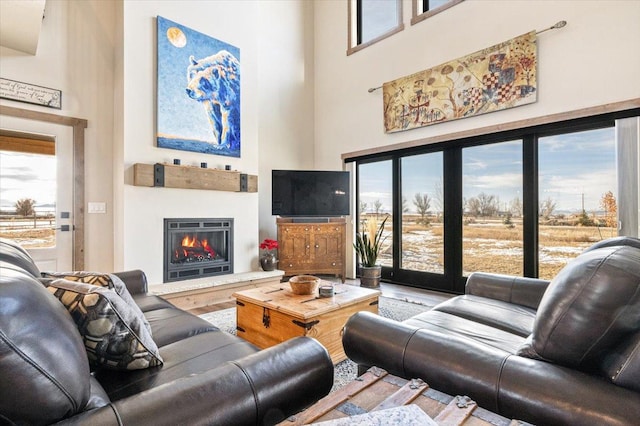 living room featuring a glass covered fireplace and a towering ceiling