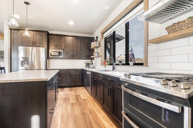 kitchen with appliances with stainless steel finishes, range hood, light wood-style floors, open shelves, and a sink