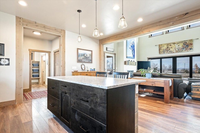 kitchen featuring light wood finished floors, light countertops, dark cabinetry, and decorative light fixtures