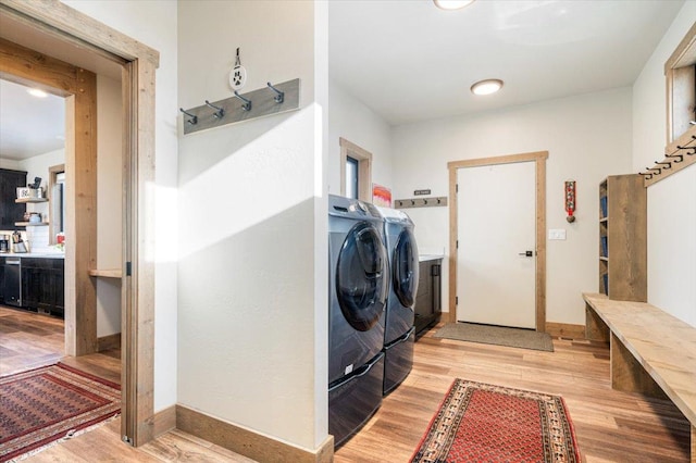 laundry room featuring laundry area, washing machine and dryer, baseboards, and light wood-style flooring