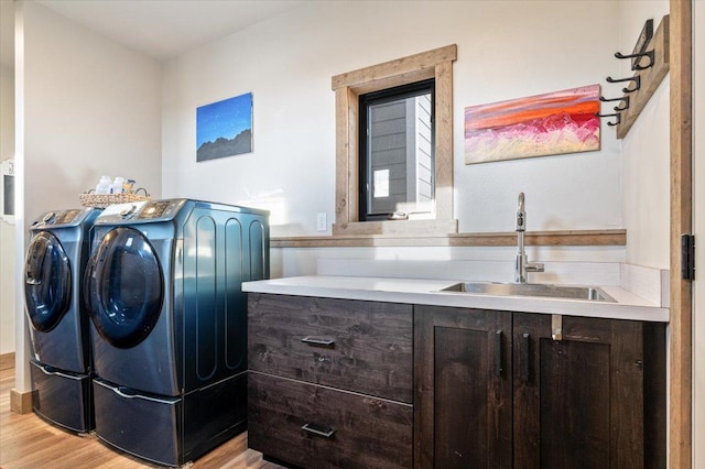 laundry area with a sink, laundry area, light wood-style floors, and washer and dryer