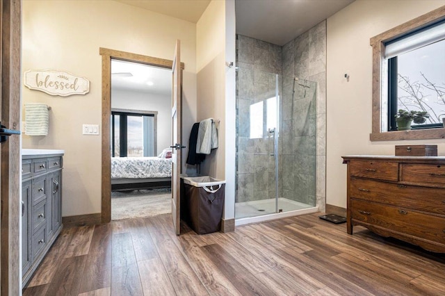 ensuite bathroom with a stall shower, ensuite bath, wood finished floors, and vanity