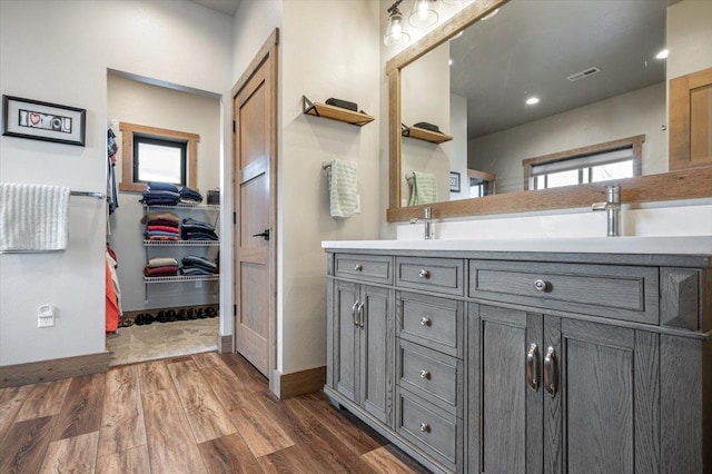 bathroom featuring double vanity, visible vents, wood finished floors, a spacious closet, and a sink