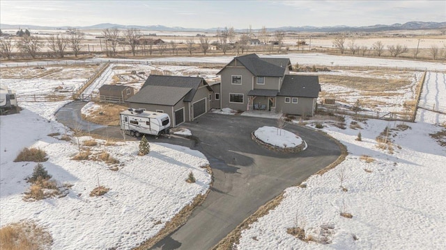 snowy aerial view with a rural view and a mountain view