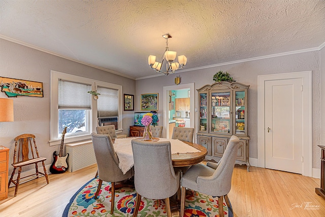 dining room featuring a notable chandelier, a textured wall, ornamental molding, a textured ceiling, and light wood-type flooring