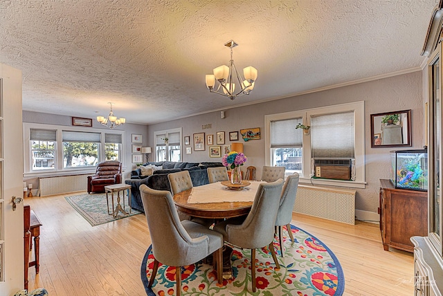 dining area with light wood-style flooring, an inviting chandelier, ornamental molding, a textured ceiling, and cooling unit