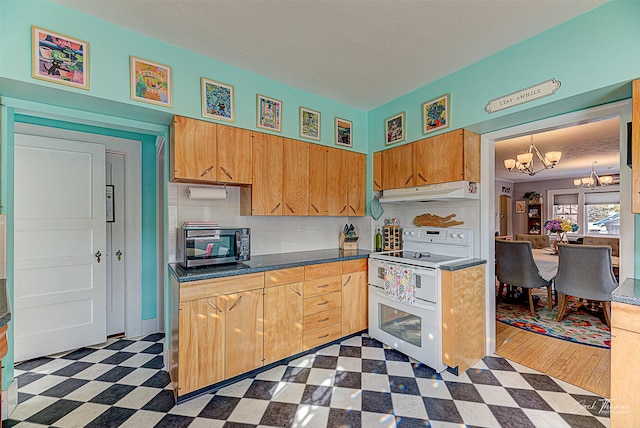 kitchen featuring dark floors, a notable chandelier, dark countertops, double oven range, and under cabinet range hood