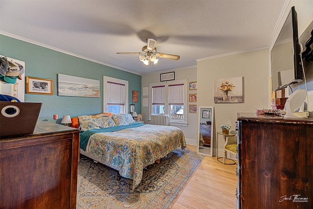 bedroom with crown molding, light wood-style flooring, a ceiling fan, a textured ceiling, and baseboards