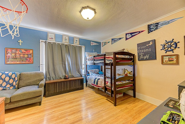 bedroom featuring crown molding, a textured ceiling, baseboards, and wood finished floors