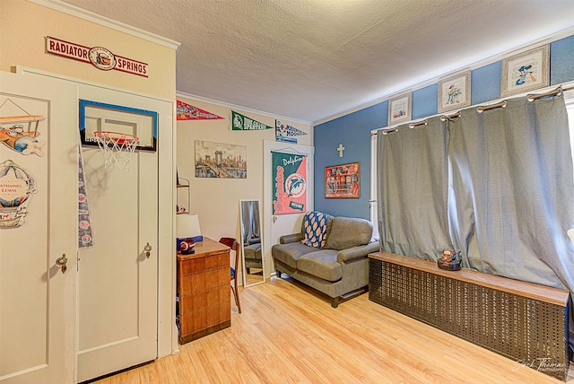 living area featuring a textured ceiling, wood finished floors, and crown molding