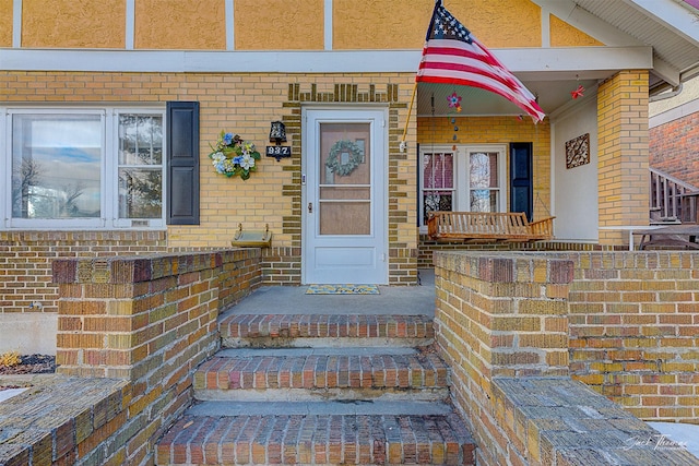 entrance to property with covered porch and brick siding