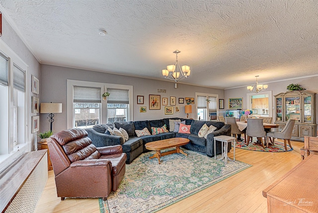 living area with a healthy amount of sunlight, light wood-style floors, and an inviting chandelier