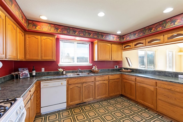 kitchen with white appliances, a wealth of natural light, a sink, and brown cabinetry