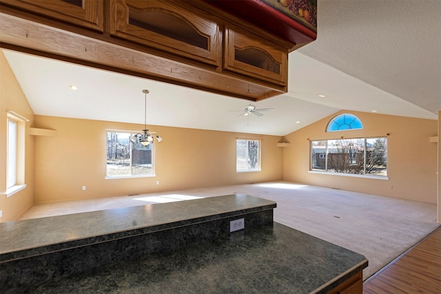 interior space featuring dark countertops, open floor plan, vaulted ceiling, and carpet