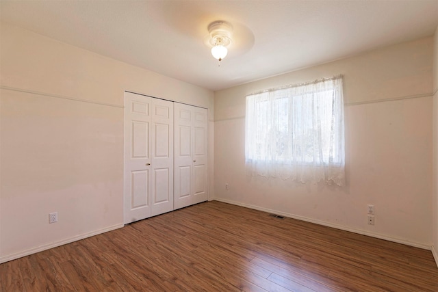 unfurnished bedroom with a closet, baseboards, and wood finished floors