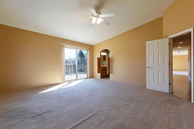 carpeted spare room featuring high vaulted ceiling, arched walkways, and ceiling fan