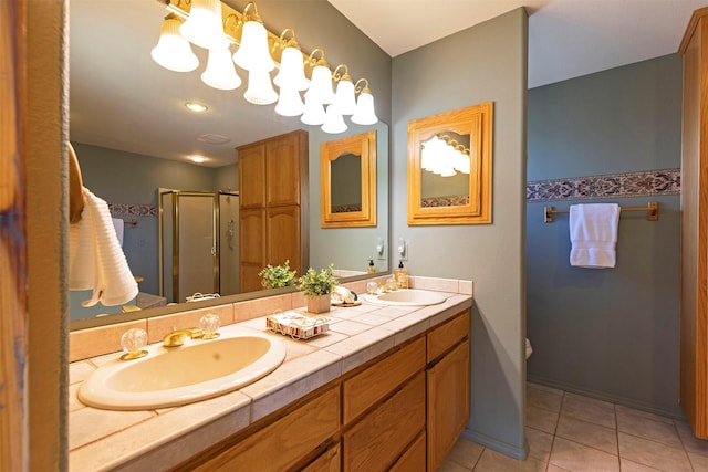 full bathroom featuring double vanity, a shower stall, a sink, and tile patterned floors