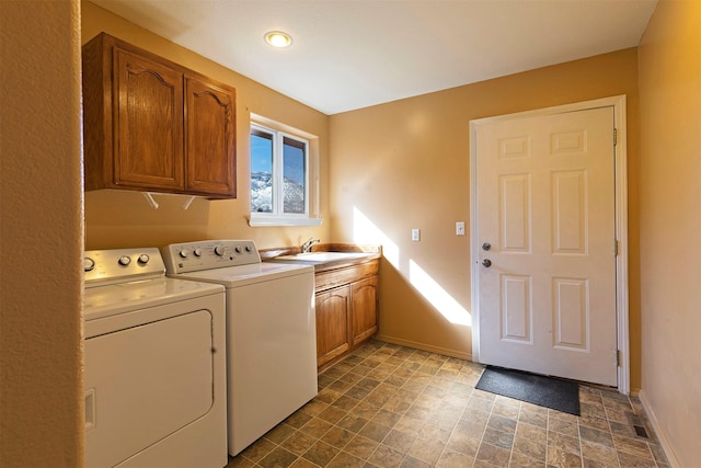 washroom featuring a sink, cabinet space, baseboards, and washer and dryer