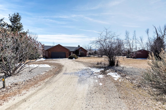 view of front of property featuring an attached garage and dirt driveway