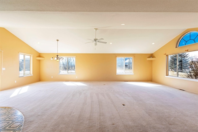 carpeted spare room with vaulted ceiling, ceiling fan with notable chandelier, and visible vents