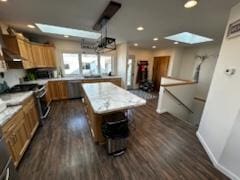 kitchen with a skylight, a center island, dark wood-style flooring, stainless steel range, and light countertops