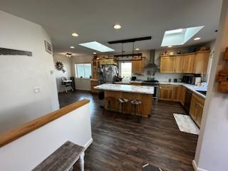 kitchen with a skylight, a center island, light countertops, and wall chimney exhaust hood