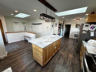 kitchen featuring a skylight, a barn door, brown cabinets, and dark wood-style flooring