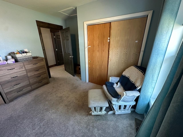 bedroom with attic access, visible vents, a closet, and light colored carpet