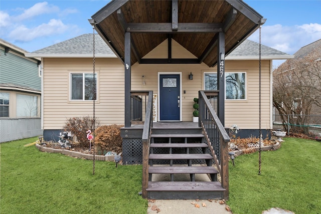 doorway to property featuring a shingled roof, fence, and a yard