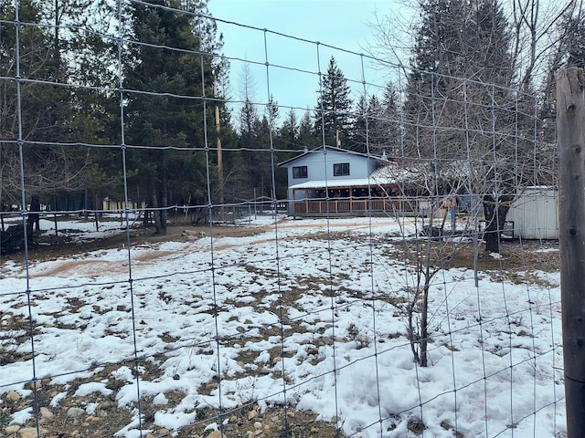 yard covered in snow featuring a wooded view